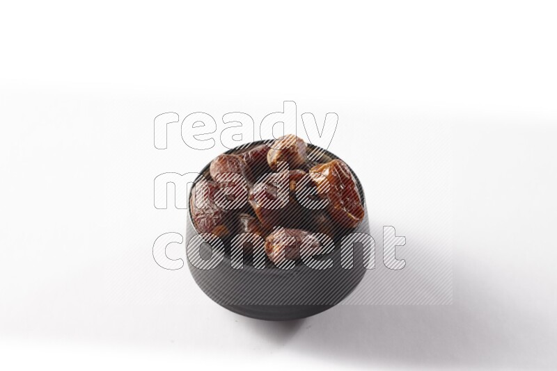Dates in a black pottery bowl on white background