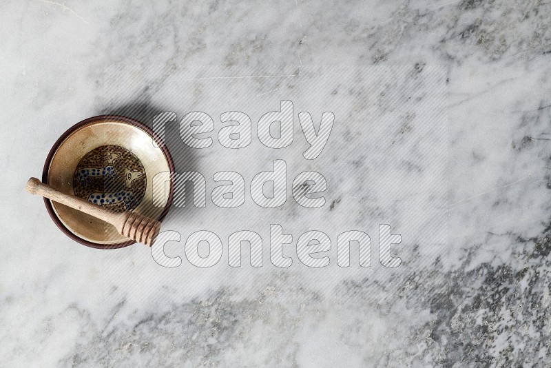 Decorative Pottery Plate with wooden honey handle in it, on grey marble flooring, Top View