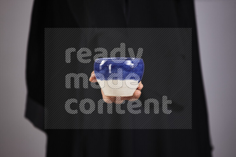 A woman in black abaya holding different pottery essentials in different positions