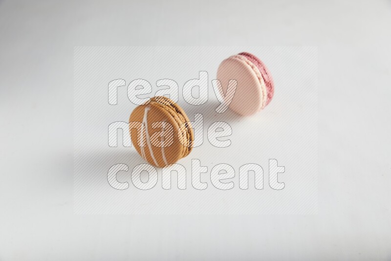 45º Shot of of two assorted Brown Irish Cream, and Pink Litchi Raspberry macarons on white background
