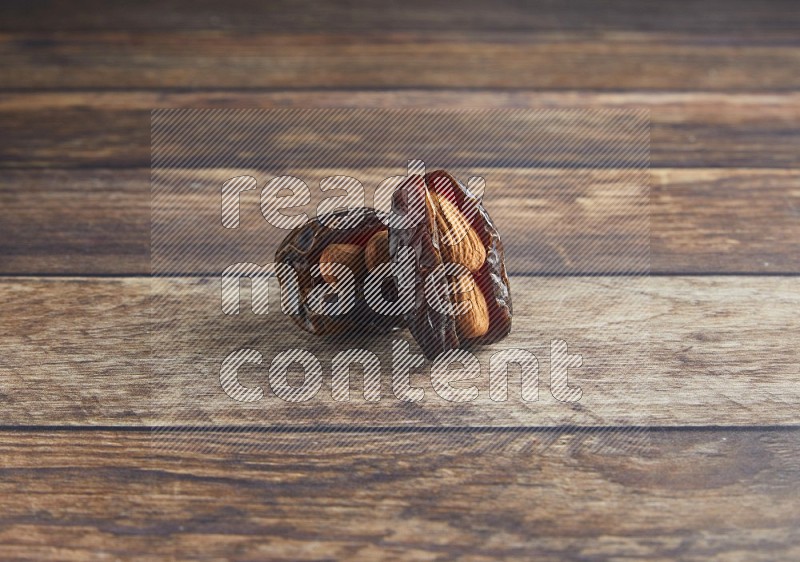 two almond stuffed madjoul dates on a wooden background