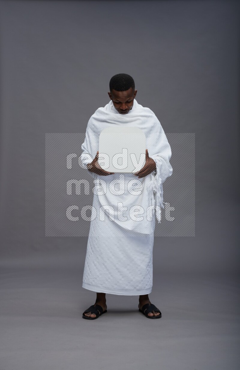 A man wearing Ehram Standing holding social media sign on gray background