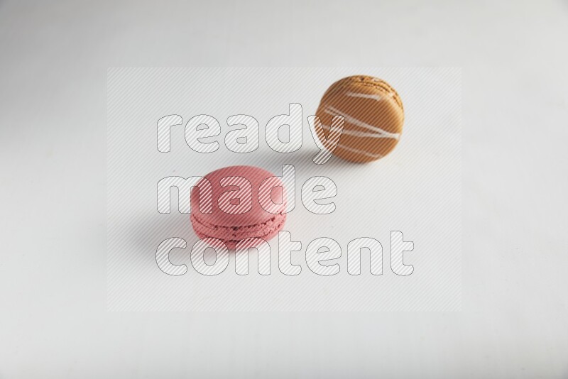 45º Shot of of two assorted Brown Irish Cream, and Pink Raspberry macarons on white background