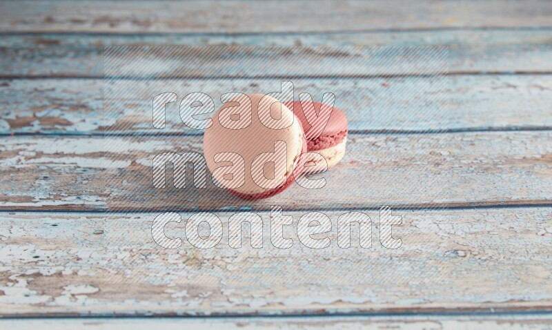 45º Shot of two Pink Litchi Raspberry macarons on light blue wooden background