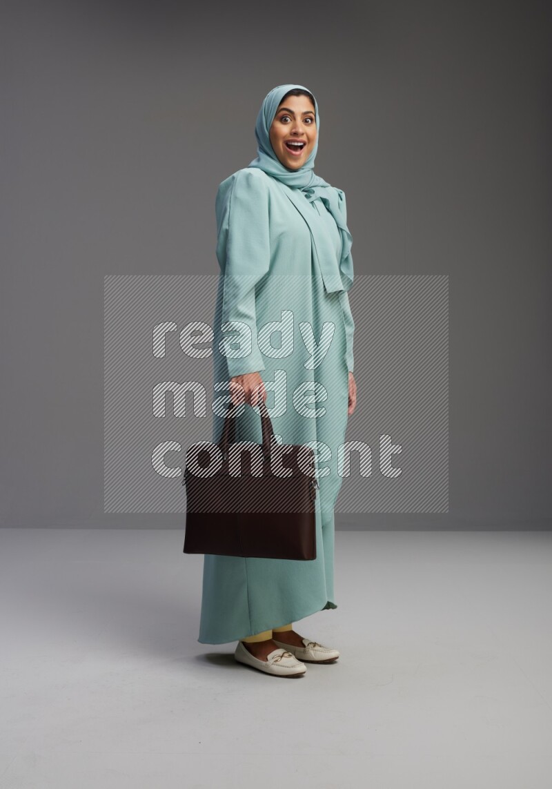 Saudi Woman wearing Abaya standing holding bag on Gray background