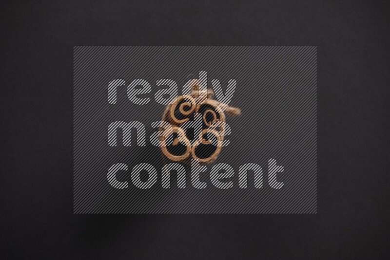 4 Cinnamon sticks stacked and bounded on black flooring