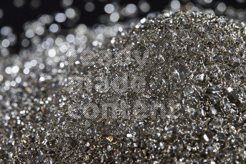 Silver shimmering fragments of glass scattered on a black background