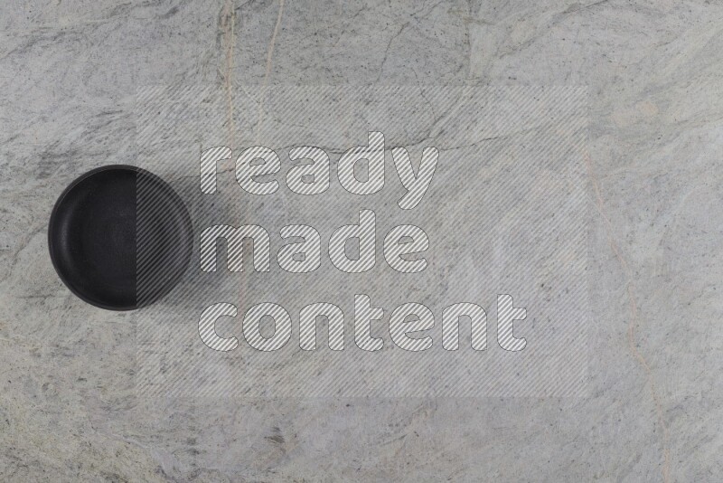 A black pottery bowl on grey marble background