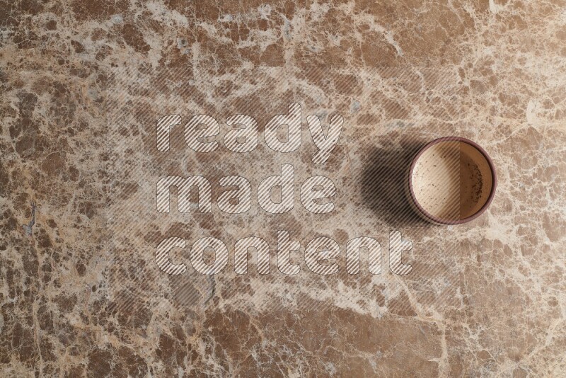 A beige pottery bowl on beige marble background