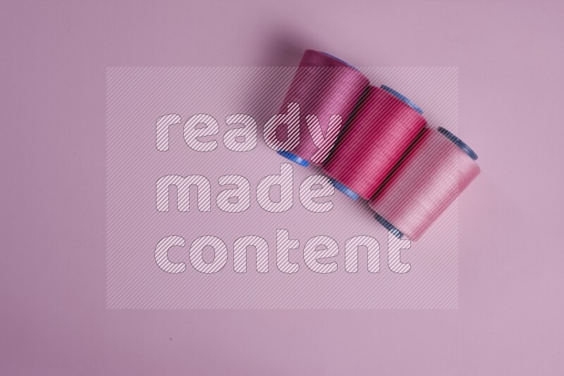 A pink collection of sewing and tailoring tools arranged on a pink background