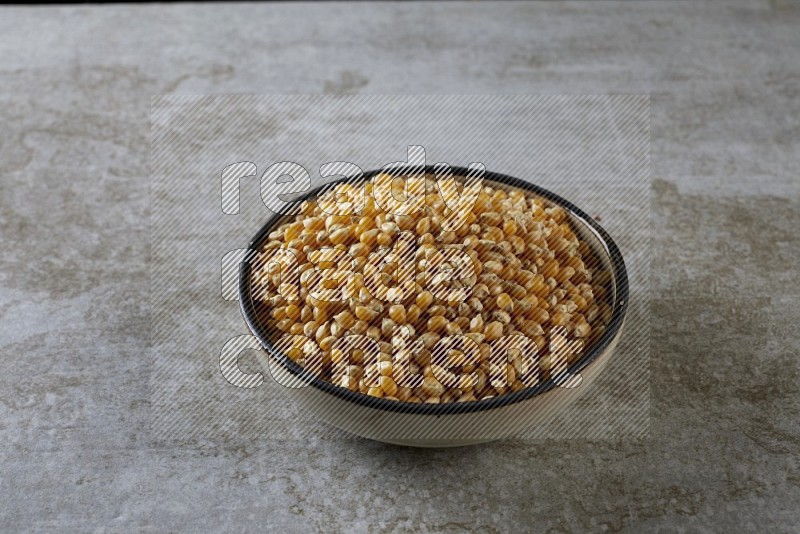corn kernel in a multi-colored pottery bowl on a grey textured countertop
