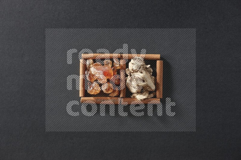 مربعان من أعواد القرفة ممتلئان بالزنجبيل المجفف والصمغ العربي علي خلفية سوداء