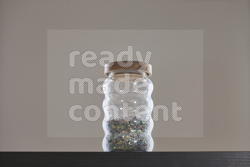 Sequins in a glass jar on black background