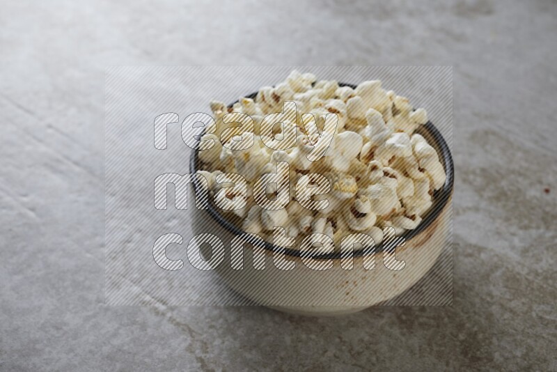 popcorn in multi-colored pottery bowl on a grey textured countertop