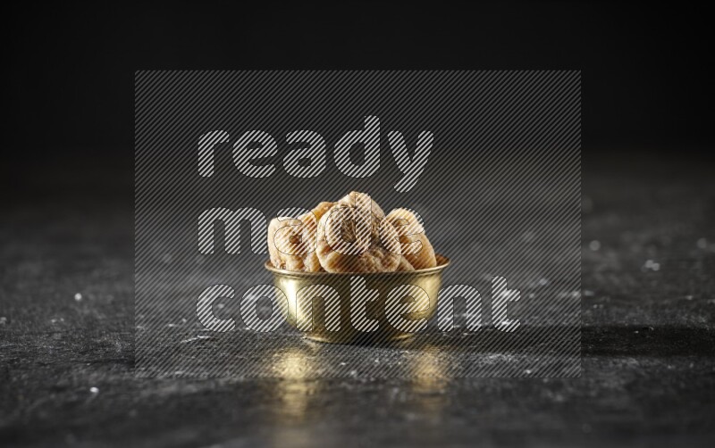 Dried fruits in a metal bowl in a dark setup