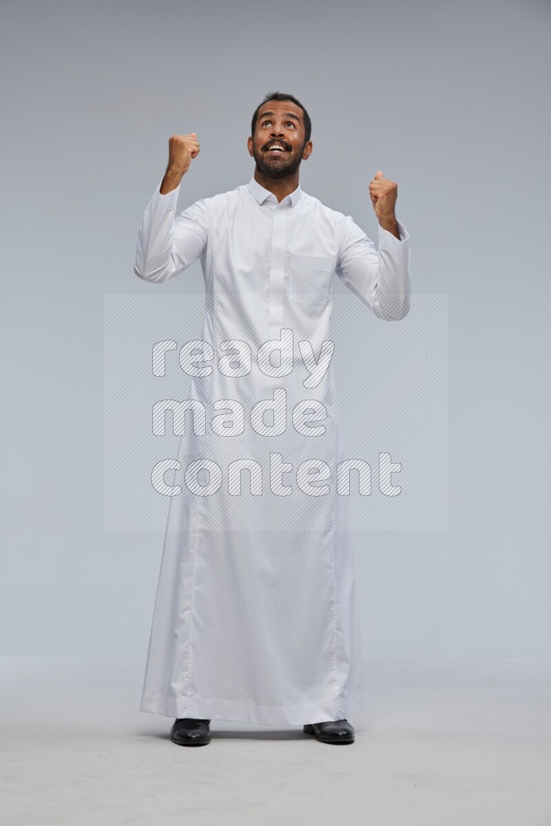 Saudi man Wearing Thob standing interacting with the camera on Gray background