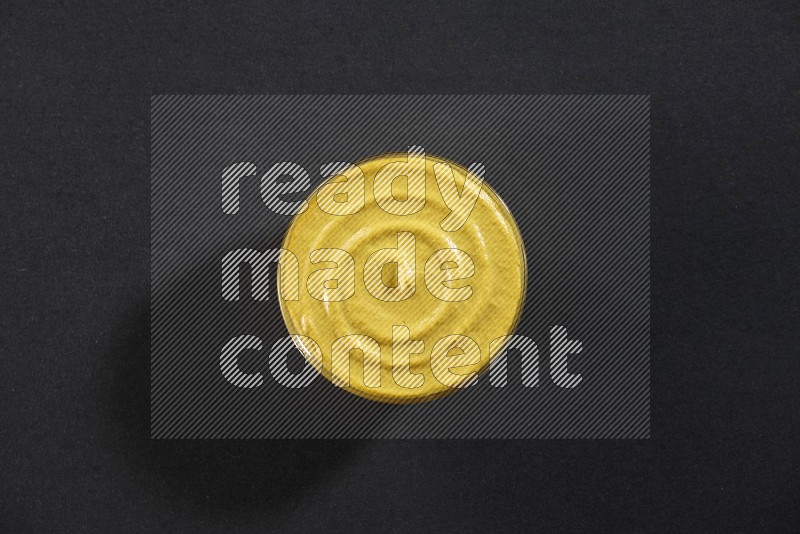 A glass bowl full of mustard paste on black flooring in different angles