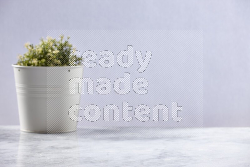 Artificial plant in white pot on grey marble background