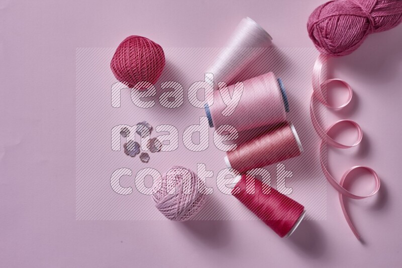 A pink collection of sewing and tailoring tools arranged on a pink background
