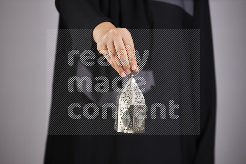 A woman in black abaya holding different ramadan lanterns in different positions