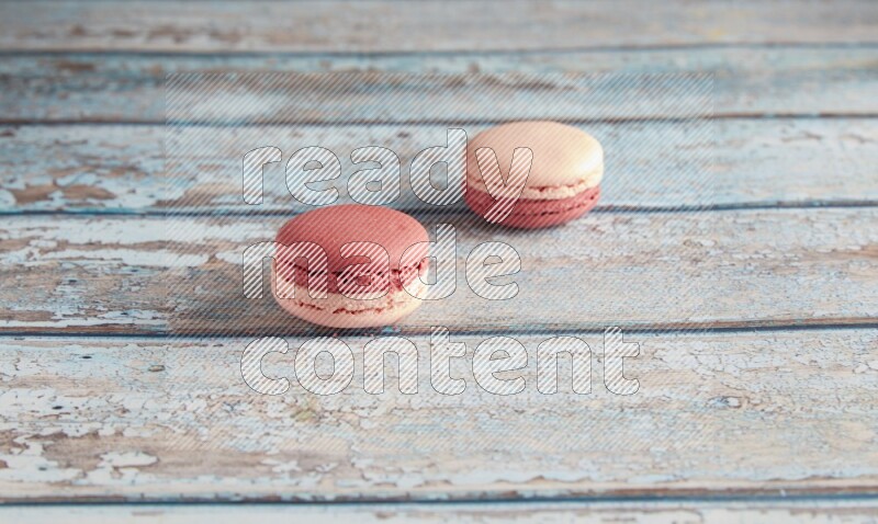 45º Shot of two Pink Litchi Raspberry macarons on light blue wooden background