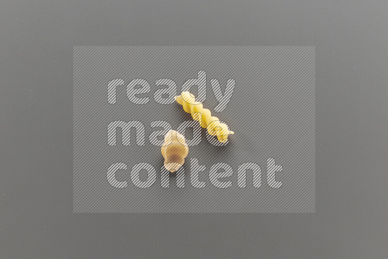 Snails pasta with other types of pasta on grey background