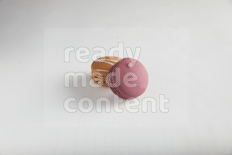 45º Shot of of two assorted Brown Irish Cream, and Red Cherry macarons on white background