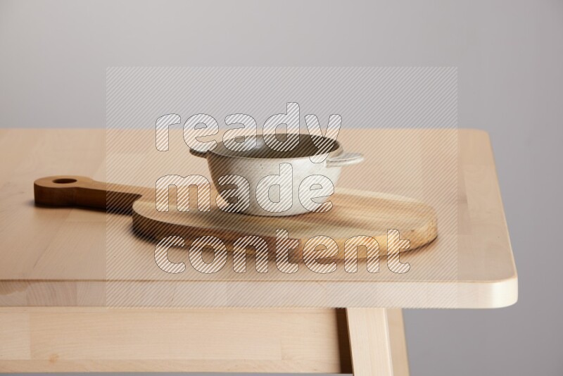 off white bowl placed on a  wooden oval cutting board on the edge of wooden table