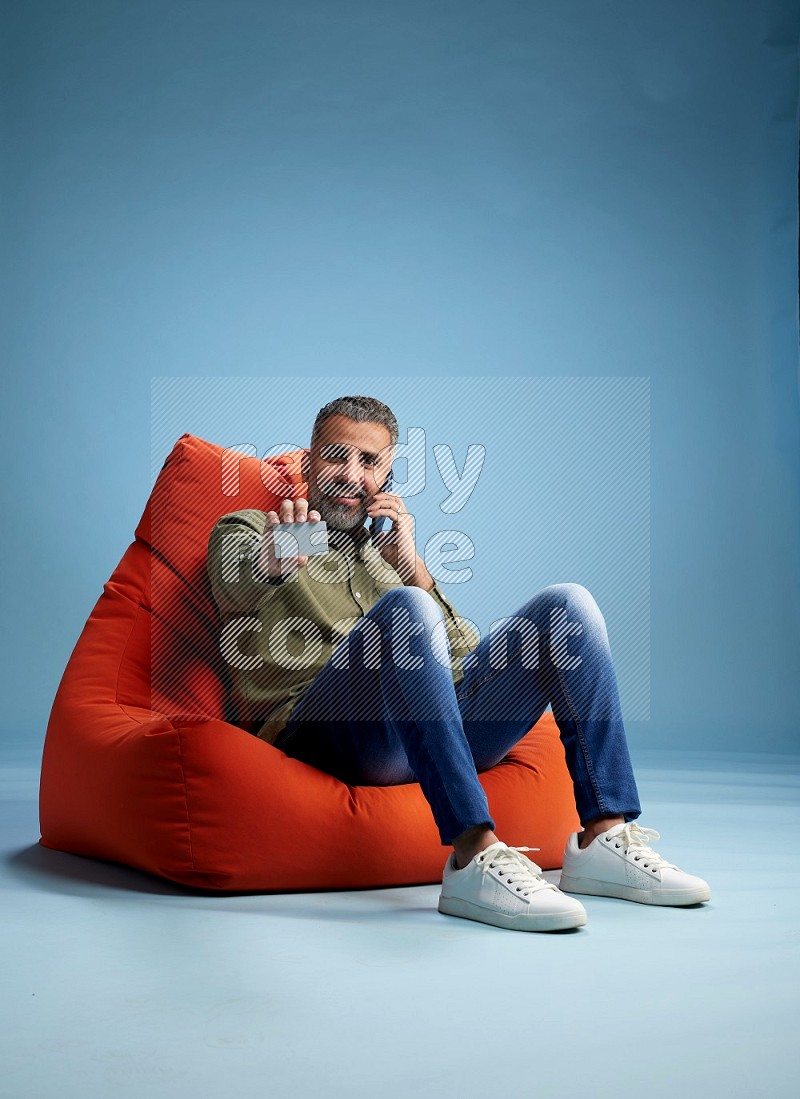 A man sitting on an orange beanbag and holding ATM card