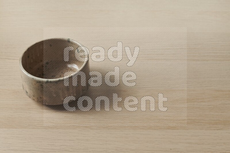 وعاء فخاري متعدد الألوان على خلفية خشبية فاتحة