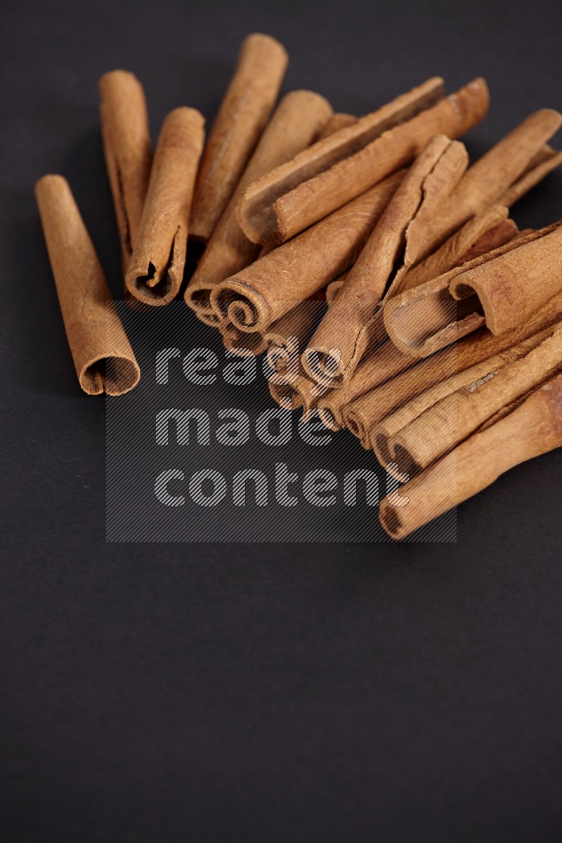 Cinnamon sticks stacked on black flooring