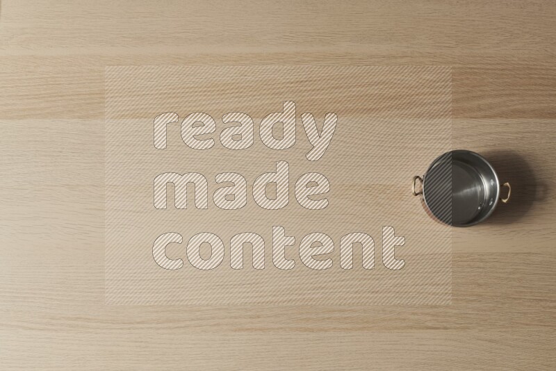 وعاء نحاسي صغير على خلفية خشبية فاتحة