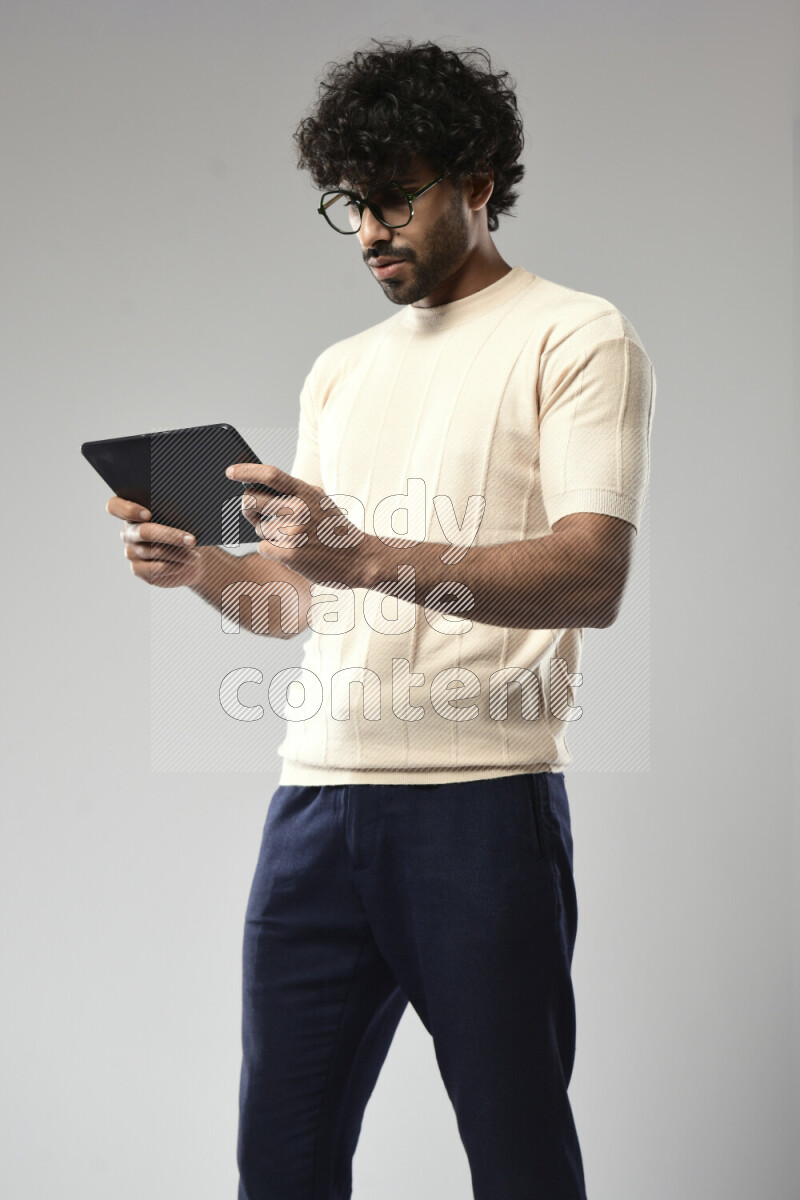 A man wearing casual standing and gaming on a tablet on white background