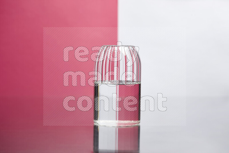 The image features a clear glassware filled with water, set against white and pink background