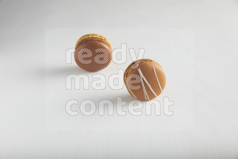 45º Shot of of two assorted Brown Irish Cream, and Yellow, and Brown Chai Latte macarons on white background