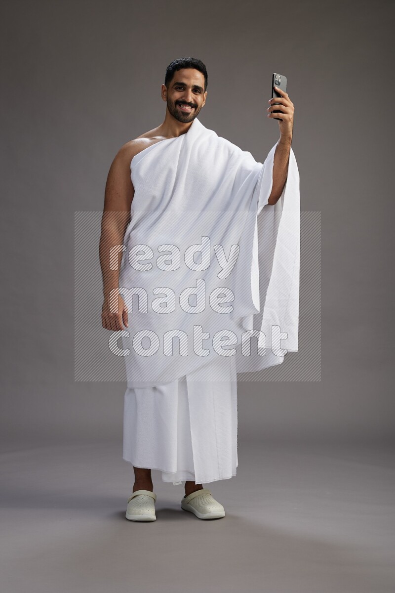 A man wearing Ehram Standing taking selfie on gray background