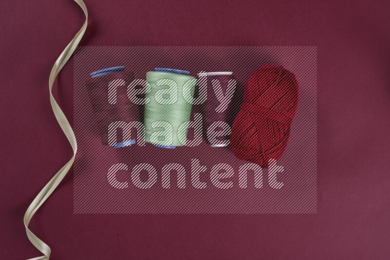 مجموعة من أدوات الخياطة والتفصيل خضراء وحمراء اللون على خلفية حمراء