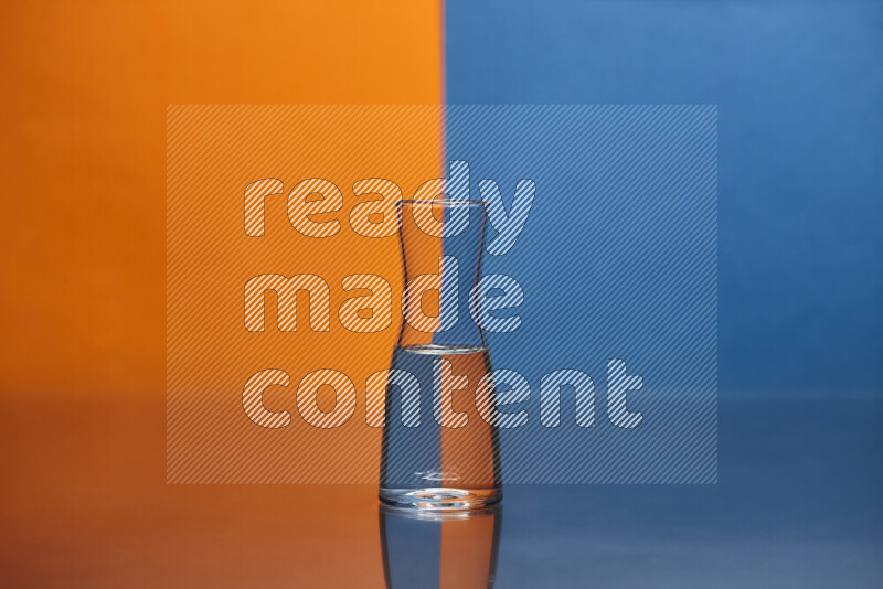The image features a clear glassware filled with water, set against orange and blue background