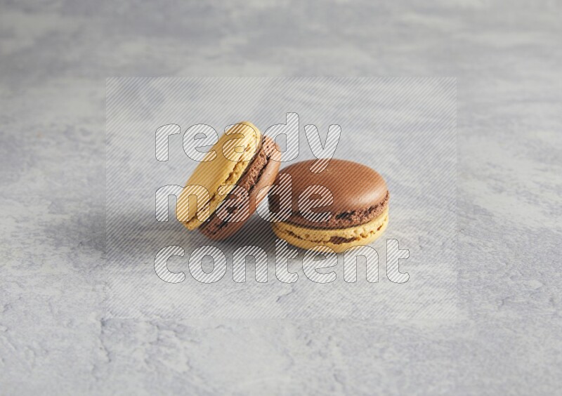 45º Shot of two Yellow and Brown Chai Latte macarons r on white  marble background