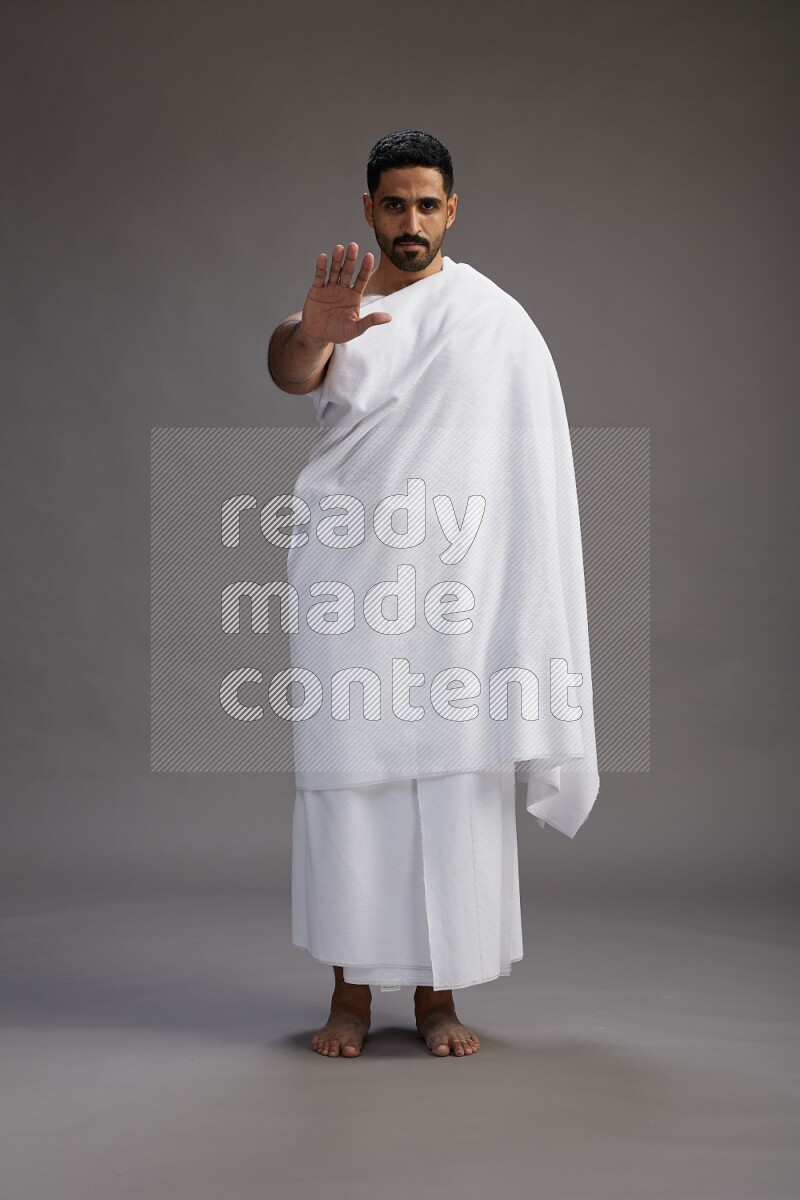 A man wearing Ehram Standing Interacting with the camera on gray background