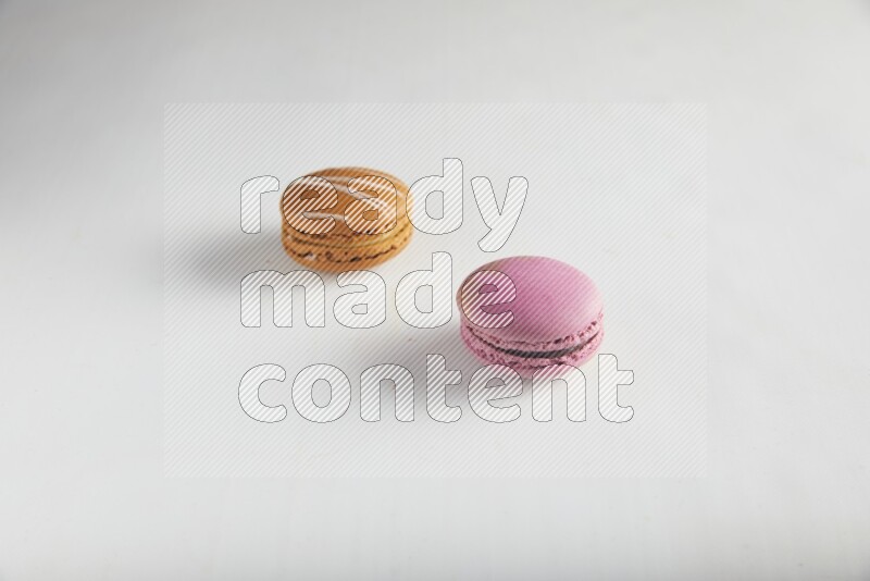 45º Shot of of two assorted Brown Irish Cream, and Purple Strawberry macarons on white background