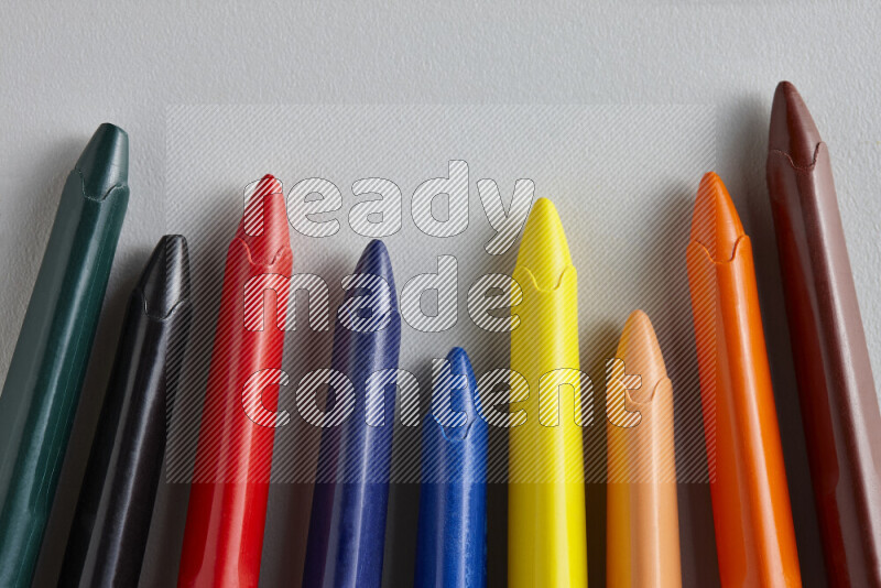 An arrangement of wax crayons in different colors on grey background