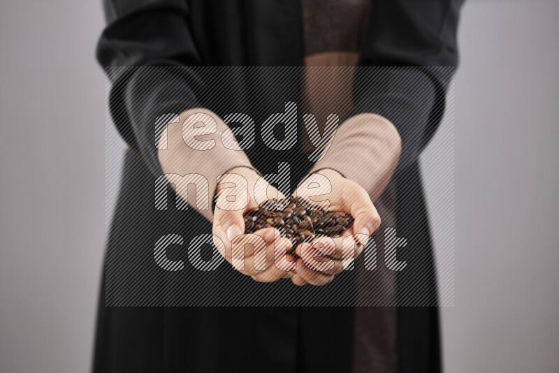 Woman in abaya holding different kinds of coffee beans in different positions