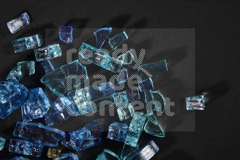 قطع زجاج زرقاء شفافة متناثرة على خلفية سوداء