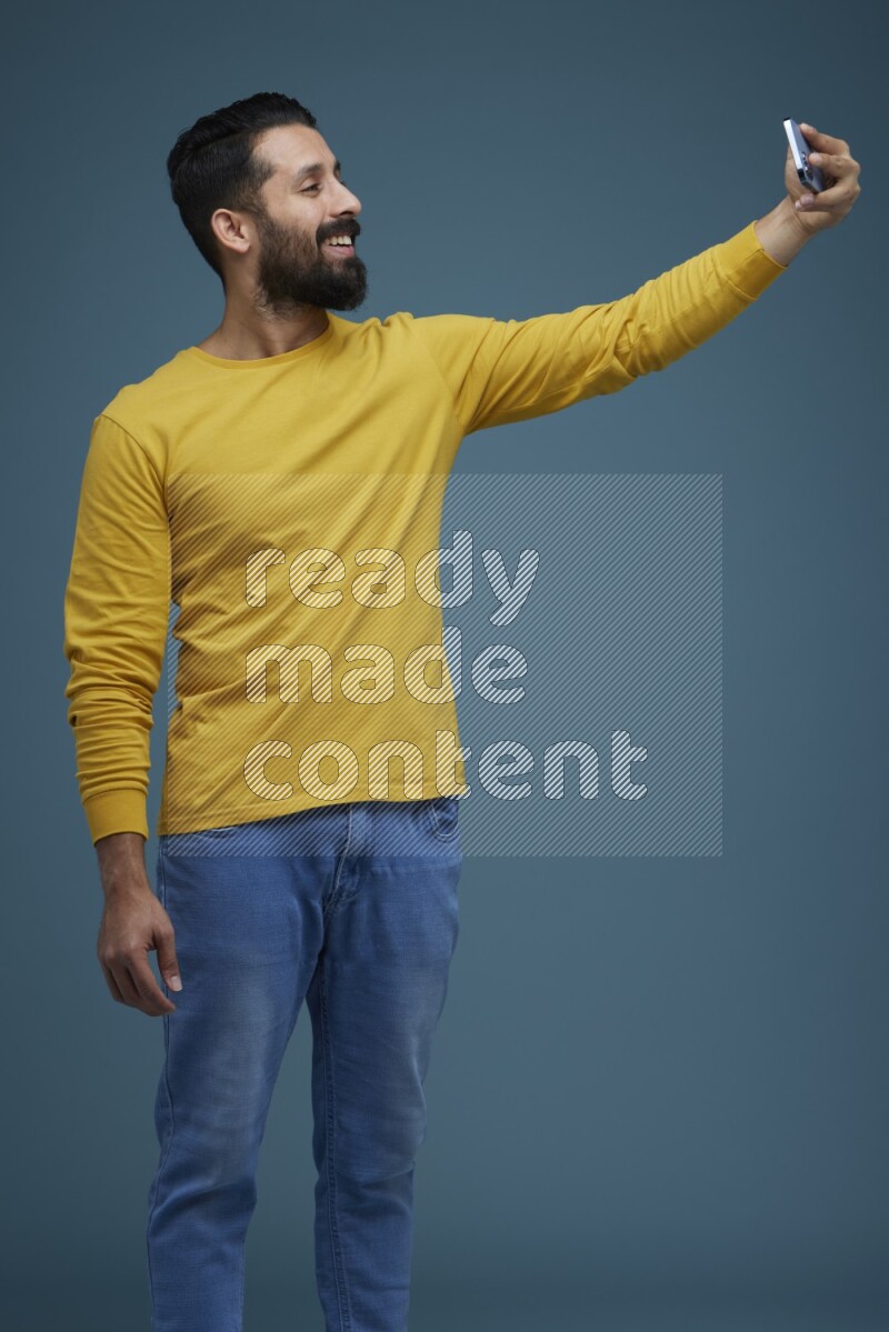 Man Taking a Selfie  in a blue background wearing a yellow shirt