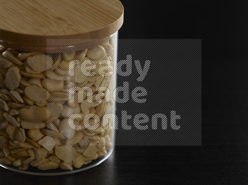Crushed beans in a glass jar on black background