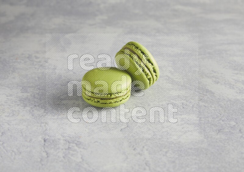 45º Shot of two Green Pistachio macarons  on white  marble background