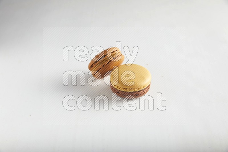 45º Shot of of two assorted Brown Irish Cream, and Yellow, and Brown Chai Latte macarons on white background