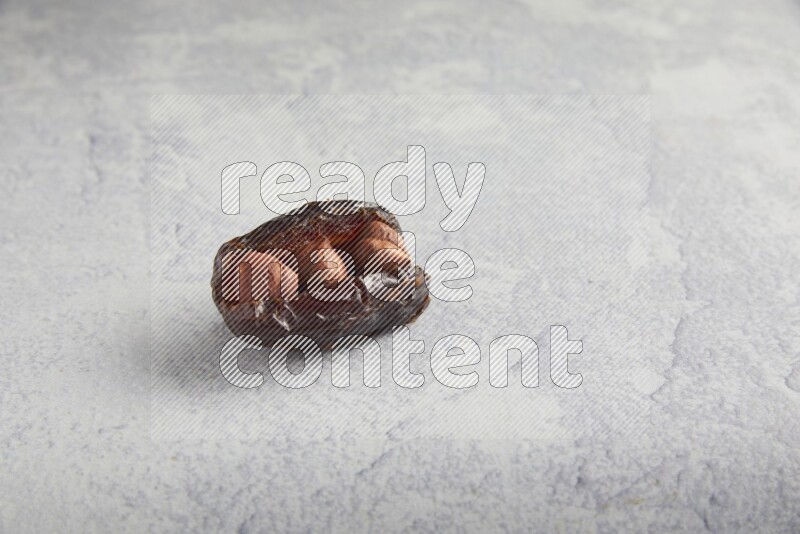 hazelnuts stuffed madjoul date on a light grey background