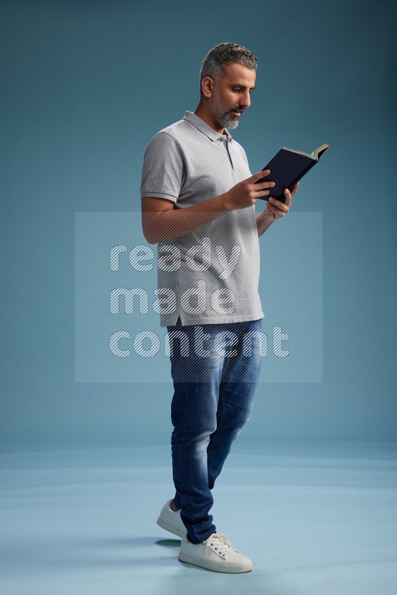 Man Standing reading book on blue background